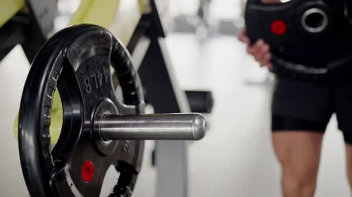 Mann wechselt Gewichte an Fitnessgeräten, Fokus auf Fitness