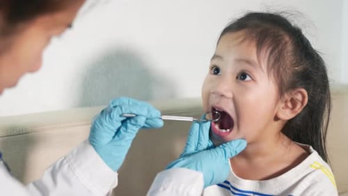 Dentist Examining Child's Teeth With Dental Mirror