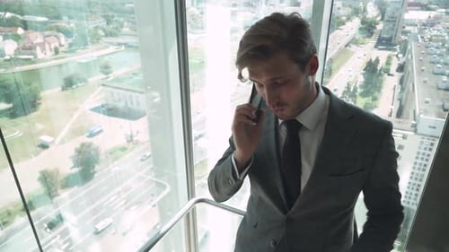 Man in Suit Talking on Phone in Glass Elevator