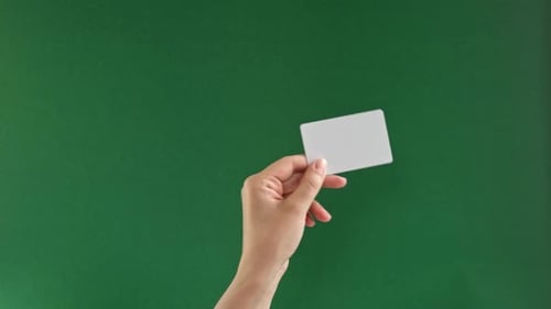 Female Hand Holding White Credit Card Isolated On Green Background