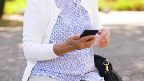 Senior Woman Using Smartphone Sitting on Park Bench