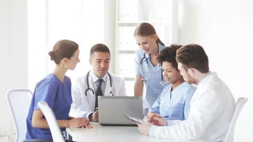 Happy doctors meeting with laptop computer discussing medical technology at hospital