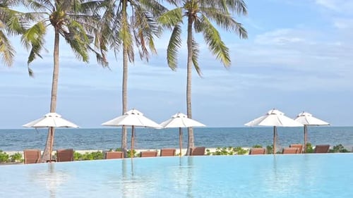 Infinity pool lounge with set up deckchairs and umbrellas in seafront beach at exotic ilsand in Thai