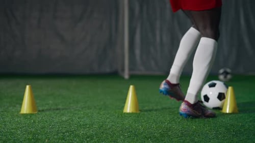 Soccer Player Skillfully Dribbling Ball Around Cones