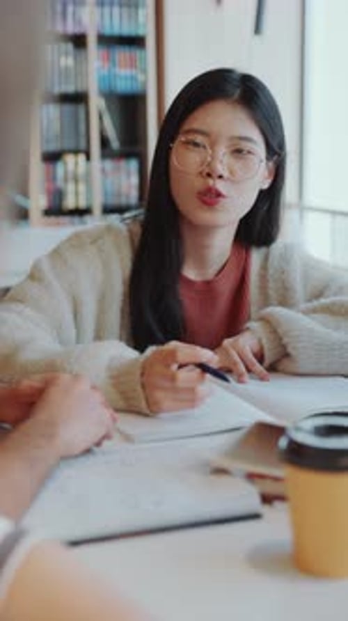 Asian Girl Talking with Other Students in College Library