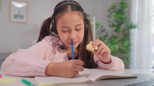 Girl Eating Cookie Doing Homework Online