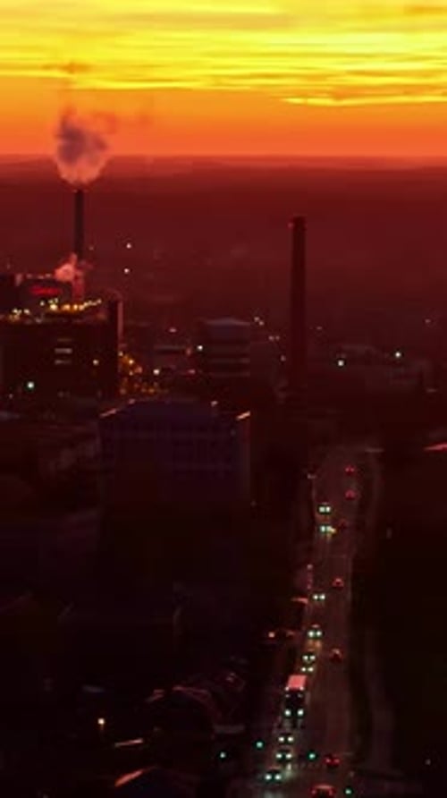 Aerial view of Jelgava skyline in Latvia with a smokestack emitting smoke and car traffic at sunset