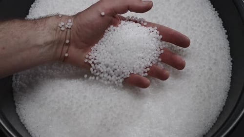 A Factory Worker Checks Plastic Pellets Before They are Put Into Production White Compound in a Man