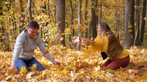 Couple Having Fun Throwing Autumn Leaves in Forest