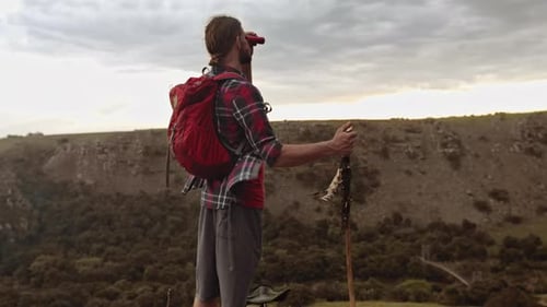 Jovem em aventura épica de caminhada nas montanhas, olhando a vista com binóculos