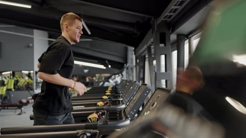 Young Man Exercising on Treadmill in Modern Fitness Center