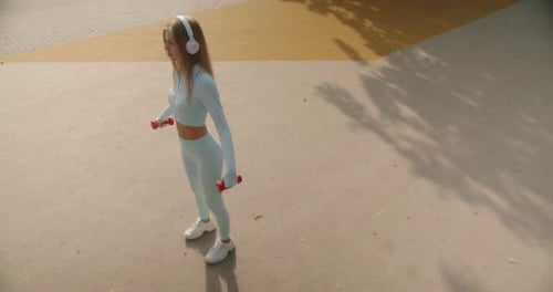 Woman Doing Dumbbell Exercise in City Park