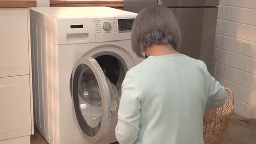 Woman Loads Laundry into Washing Machine at Home
