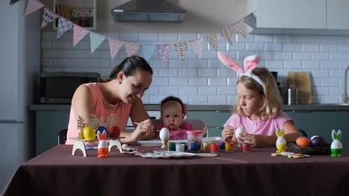 Family Decorating Easter Eggs Together in Kitchen