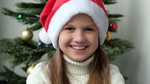 Smiling Girl Wearing Santa Hat with Christmas Tree