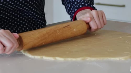 Hands Rolling Dough with Rolling Pin on Counter