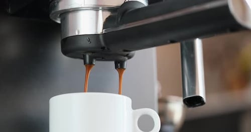 Home Espresso Making Process Coffee Stream Pouring From Machine Into Ceramic Cup
