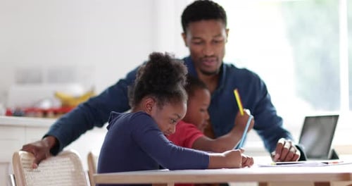 Man Helping Young Girl with Schoolwork at Home