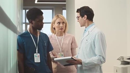 Doctor Talking to Nursing Assistants at Hospital Corridor