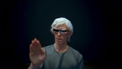 Man Wearing Futuristic Glasses Gesturing in a Dark Studio