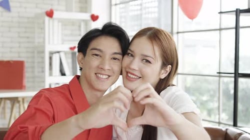 Young Couple Smiling and Forming Heart Shape with Hands
