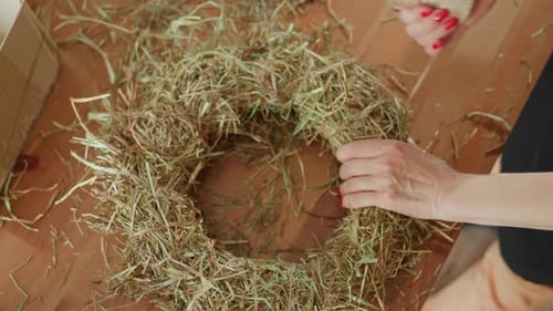 Woman Crafts Rustic Wreath with Twine and Hay
