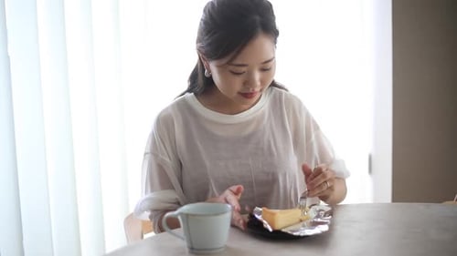 Woman Eating Cheesecake Slice at Bright Table
