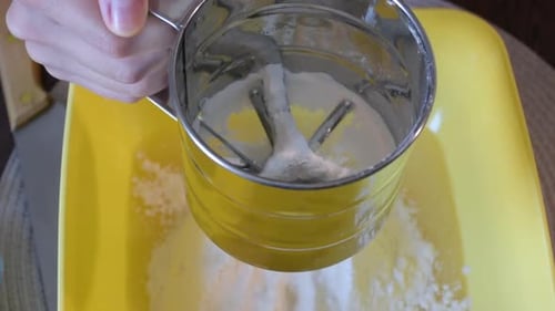 Sifting White Flour on Bright Yellow Bowl