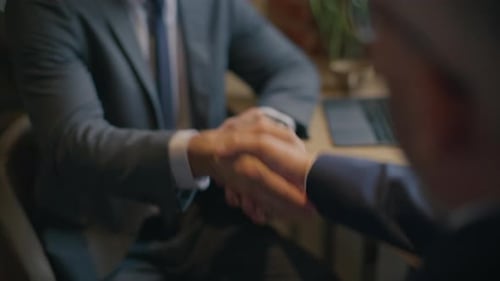 Close Up of Two Businessmen Shaking Hands after Discussion in Cafe