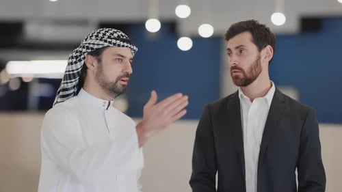 MultiEthnic Couple of Business Office Manager and Arabic Entrepreneur Communicating and Smiling in