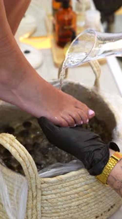 Beautician pouring water for feet spa treatment