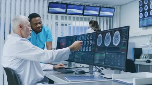 Medical Scientist and Surgeon Discussing CT / MRI Brain Scan Images on a Personal Computer in Labor