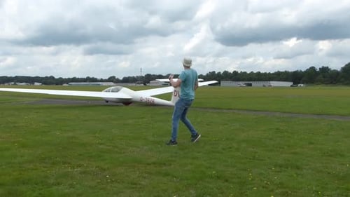 winch launch of a white glider across a white into the cloudy sky