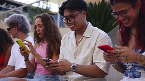 Five Young Adults Using Smartphones Together Outdoors