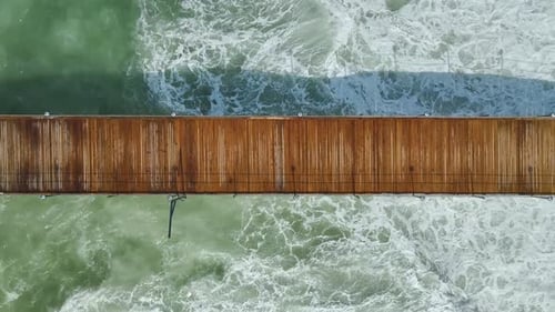 Vídeo aéreo do deck do resort que se estende até o mar aberto com espreguiçadeiras dispostas em fileiras organizadas