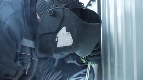 Welder in protective helmet uses welding. Welder Welds a metal pipe. Iron welding. Welding Sparks