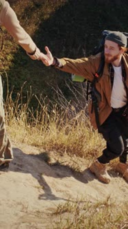 Hikers Helping Each Other Up Grassy Hill