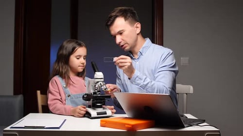 Father and Daughter Exploring Science with a Microscope
