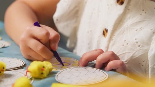 Les enfants décorent des œufs de Pâques tout en étant assis à la table à la maison, les mains rapprochées
