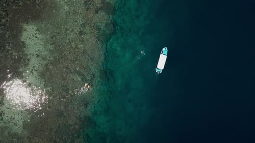 Aerial View of Boat in Komodo Island’s Clear Turquoise Waters with Snorkelers and Aquatic Life