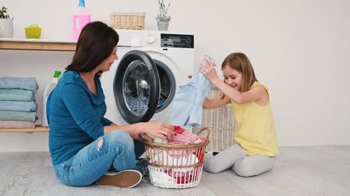 Mutter und Tochter laden Kleidung zum Waschen
