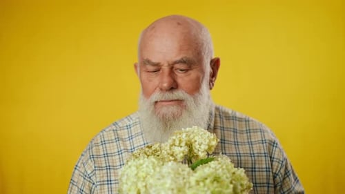 Senior Man Smells Flowers in Close Up