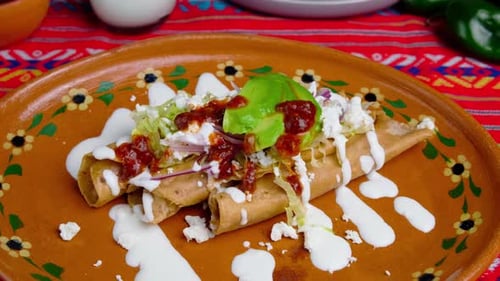 Delicious Flautas Garnished with Avocado, Cheese, and Sauce