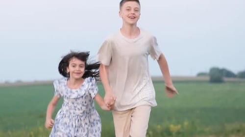 Children Running Through a Green Field Holding Hands