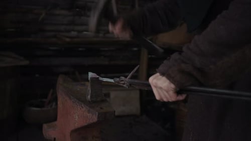 Hands of Unrecognizable Blacksmith Forging Iron Fixture on Anvil with Hammer