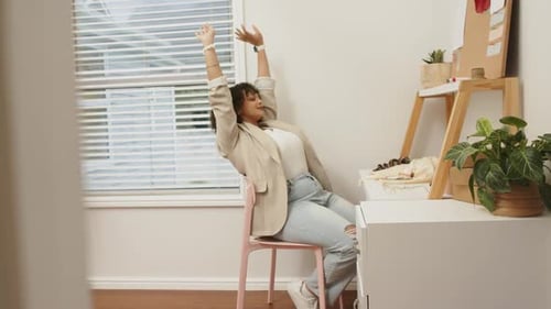 After home office work, African American woman stretching wrists glancing out window, resuming work