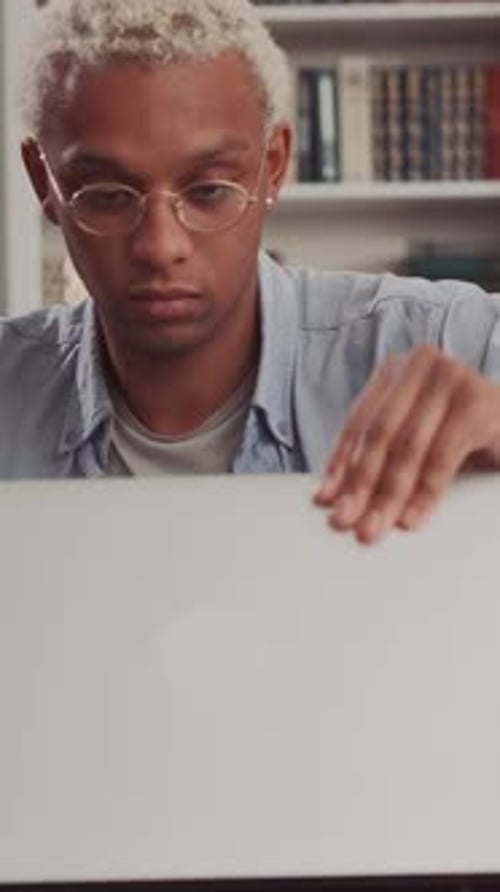 Focused African American Male Studying at Desk With Laptop and Books