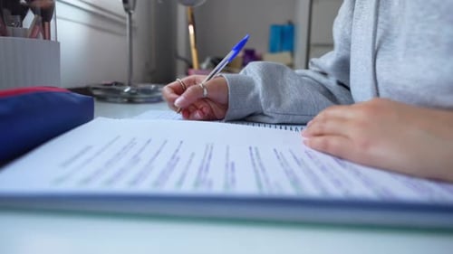 Student Writing on Paper at Bright Desk