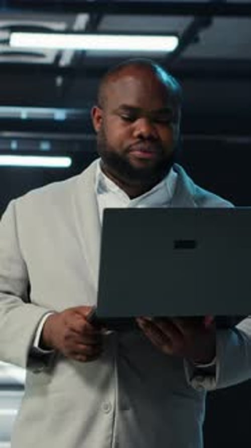 Vertical Video Data Center Engineer Coding on Laptop Doing Software Updates for Mainframes