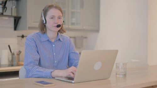 Thumbs Up by Young Woman with Headset in Call Center